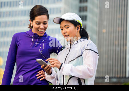 Läufer mit Handy in der Nähe von Hochhäusern Stockfoto