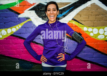 Hispanische Läufer lächelnd in der Nähe von Graffitiwand Stockfoto