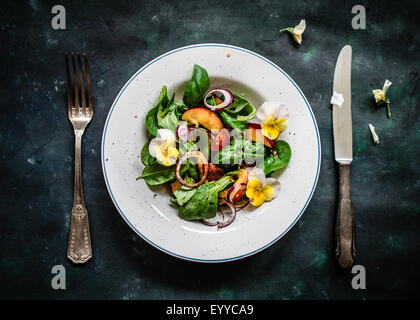 Bunter Sommersalat mit Nektarinen und essbaren Blüten. Ansicht von oben. Stockfoto