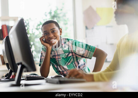 Schwarzer Student lächelnd in der Nähe von Computern im Klassenzimmer Stockfoto