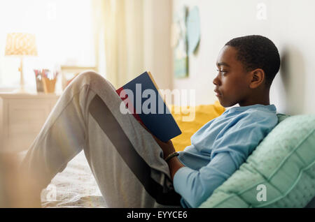 Schwarzer Junge Buch auf Bett Stockfoto
