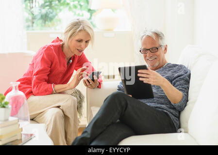 Älteres kaukasischen Ehepaar mit Technologie im Wohnzimmer Stockfoto