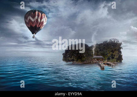 Heißluft-Ballon schwebt über Haus auf tropischen Insel Stockfoto