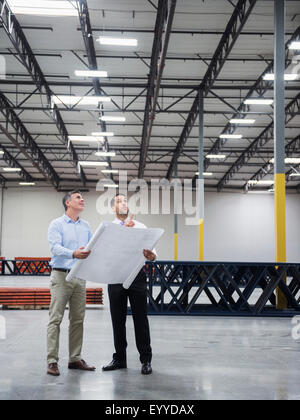 Kaukasische Architekten lesen Blaupausen in Lager Stockfoto