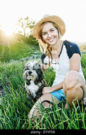 Kaukasische Frau Petting Hund im Feld Stockfoto