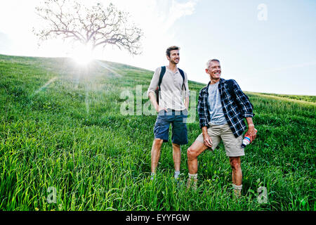 Kaukasische Vater und Sohn auf grasbewachsenen Hang stehend Stockfoto