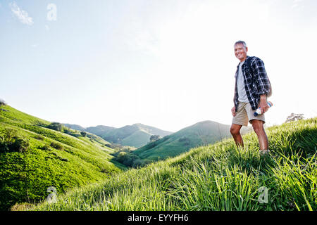 Älteren kaukasischen Mann lächelnd auf grasbewachsenen Hang Stockfoto