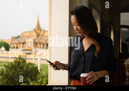 Asiatische Geschäftsfrau mit Handy am Fenster, Phnom Penh, Kambodscha Stockfoto