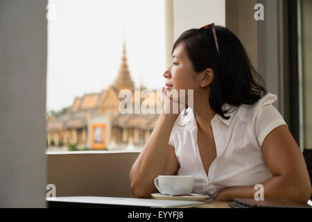 Asiatische Frau schaut aus Café Fenster, Phnom Penh, Kambodscha Stockfoto