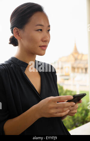 Asiatische Frau mit Handy am Fenster, Phnom Penh, Kambodscha Stockfoto