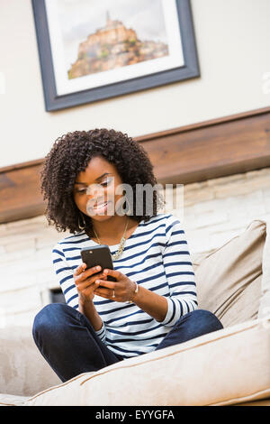 Schwarze Frau mit Handy auf sofa Stockfoto