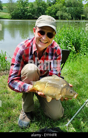 Karpfen, Karpfen, europäischen Karpfen (Cyprinus Carpio), Angler mit Gefangenen Spiegelkarpfen, Deutschland, Baden-Württemberg Stockfoto