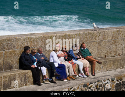 Menschen, die Zuflucht vor Wind am Meer bei St. Ives, Cornwall, England, UK Stockfoto