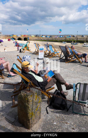 Mann und Frau mit Hund sitzen in Liegestühlen am Hafen von St. Ives, Cornwall, England, UK Stockfoto