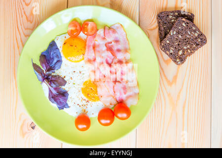 Spiegeleier mit Speck und zwei Scheiben Brot mit Körnern Stockfoto