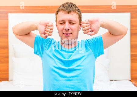 Glücklicher Mann dehnen im Bett aufgewacht Stockfoto