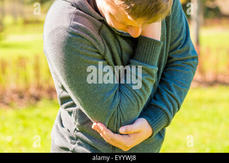 junger Mann packte Hand wund Ellenbogen Stockfoto