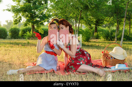 zwei Spion Mädchen verstecken Gesicht hinter dem Buch Pin-up- Stockfoto