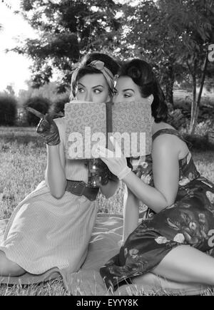 zwei Spion Mädchen verstecken Gesicht hinter der Buch-retro Stockfoto