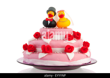 Rosa Hochzeitstorte und lustiges paar Enten mit roten Rosen isoliert auf weißem Hintergrund Stockfoto