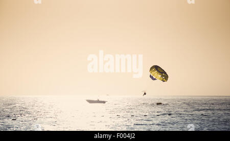 Parasailing am Fallschirm über Wasser bei Sonnenuntergang Stockfoto