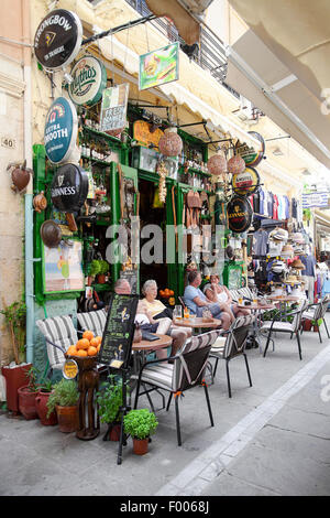 Touristen genießen einen Drink außerhalb einer irischen Bar im Stil, inmitten der alten kretischen Stadt Rethymnon auf der griechischen Insel Kreta. Stockfoto