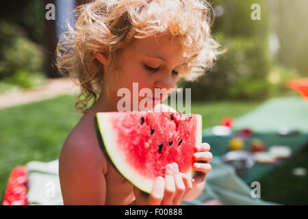 Kleine Mädchen essen Wassermelone auf dem Rasen im Sommer Stockfoto