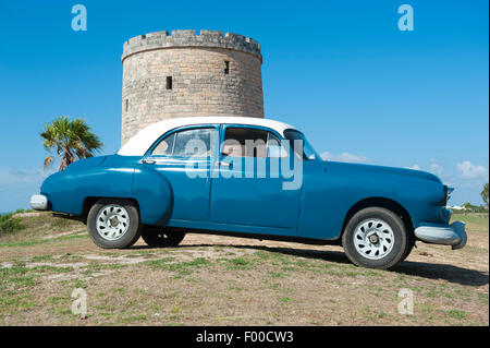 VARADERO, Kuba - 7. Juni 2011: Klassische amerikanische Oldtimer parkte vor einem Stein Wachturm erbaut in den 1930er Jahren. Stockfoto