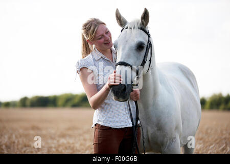 Eine junge Frau in einem Weizenfeld streicheln einen Pferde-Maulkorb Stockfoto