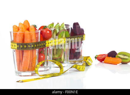 Konzeptbild - frisches Obst und Gemüse im Glas Tassen mit Maßband auf weißem Hintergrund. Stockfoto