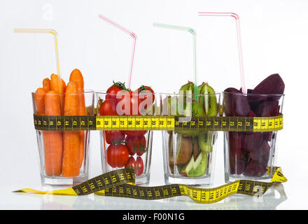 Konzeptbild - frisches Obst und Gemüse im Glas Tassen mit Maßband auf weißem Hintergrund. Stockfoto