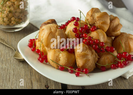 Windbeutel und roten Johannisbeeren auf weißen Teller selektiven Fokus horizontal Stockfoto