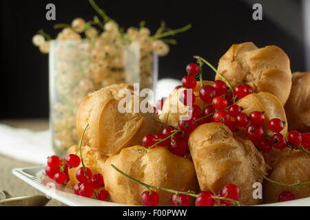 Windbeutel und roten Johannisbeeren auf weißen Teller selektiven Fokus horizontale closeup Stockfoto