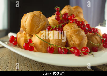 Windbeutel und roten Johannisbeeren auf weißen Teller selektiven Fokus Stockfoto