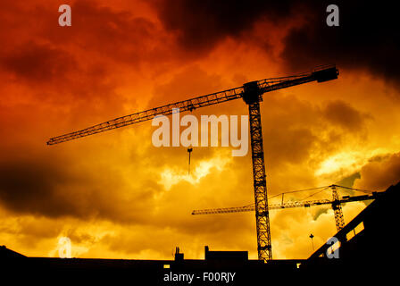 Baustelle mit Kranen in der Silhouette gegen einen Sonnenuntergang Stockfoto