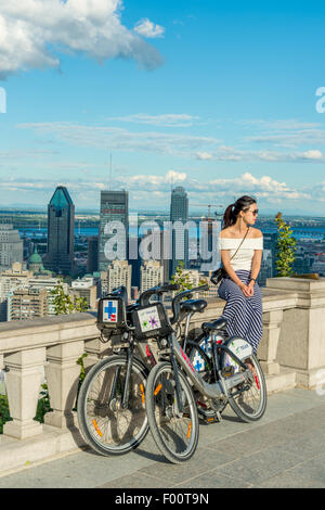 Eine junge Asiatin auf der Terrasse des Kondiaronk Belvedere auf dem Mont-Royal Mountain in Montreal, neben Bixi Bike. Stockfoto