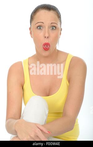 Junge Frau mit einem Sinn für Humor gefangen Off Guard Grimassen trägt eine helle gelbe Weste Top gegen einen weißen Hintergrund isoliert Stockfoto