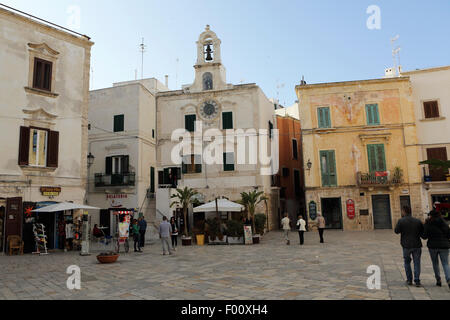 Geschäfte, Cafés und den Glockenturm einer Matriarchal Kirche (Chiesa Matrice) in Polignano a Mare in Apulien, Italien. Stockfoto