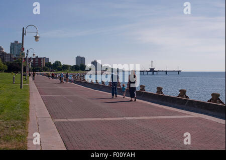 Die Menschen gehen am Wegesrand Waterfont in Burlington, Ontario. Brant Street Pier können in der Ferne gesehen werden. Stockfoto