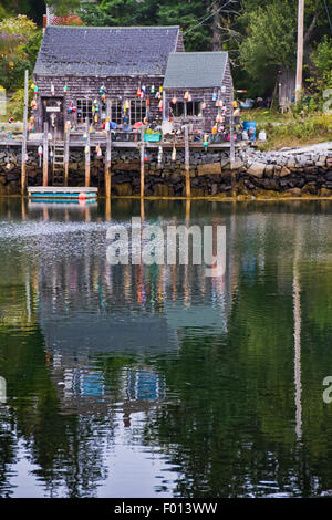 Ein kleines Bootshaus verziert mit bunten Liegeplatz Kugeln und Krabbenfalle schwebt durch den Port Clyde Hafen in Maine Stockfoto