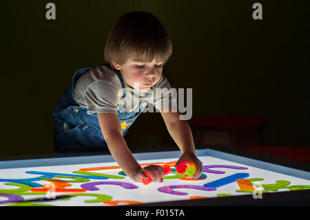 Vier Jahre alter Junge spielt mit farbigen Objekten Leuchtkasten am Kentucky Science Center in Louisville Kentucky Stockfoto