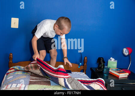 Kleiner Junge (sieben Jahre alt) macht sein Bett in den Morgen.  HERR Stockfoto