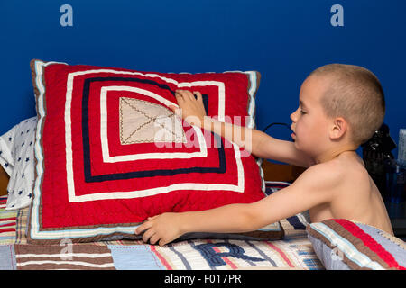 Kleiner Junge (sieben Jahre alt) macht sein Bett in den Morgen.  HERR Stockfoto