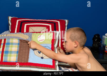 Kleiner Junge (sieben Jahre alt) macht sein Bett in den Morgen.  HERR Stockfoto