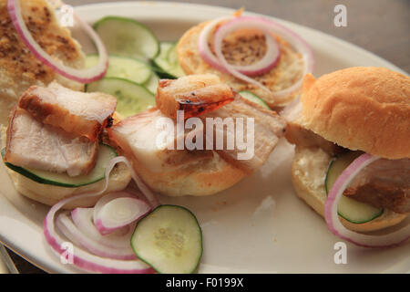 Eine Platte mit gebratenen Schweinebauch, Gurken, Zwiebeln und kleine Brötchen mit Vollkorn-Senf Stockfoto