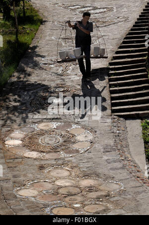 Tongchuan, chinesischen Provinz Shaanxi. 5. August 2015. Ein Arbeiter der Chenlu Keramik Fabrik von Yaozhou Brennofen trägt Keramik Adobes in der antiken Stadt Chenlu in Tongchuan Stadt, Nordwesten der chinesischen Provinz Shaanxi, 5. August 2015. Chenlu, bekannt für die Herstellung von Keramik seit der Yuan-Dynastie (1271-1368), bewahrt seine Öfen in Brand. Seine 120-odd Öfen wurden als wichtige kulturelle Relikte unter staatlichem Schutz im Jahr 2006 aufgeführt. © Tao Ming/Xinhua/Alamy Live-Nachrichten Stockfoto