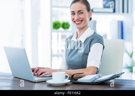 Glücklich Geschäftsfrau auf Laptop-Computer arbeiten und Blick in die Kamera Stockfoto