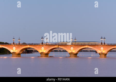 Verschwommene Straßenbahn über die Pont de Pierre-Brücke über den Fluss Garonne bei Sonnenuntergang in Bordeaux, Frankreich Stockfoto