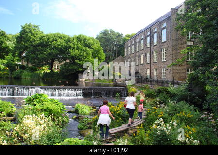 Menschen gehen über die öffentlichen Holzsteg durch Bamford Mill und Wehr in den Peak District Derbyshire England UK - Sommer Stockfoto