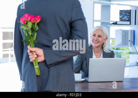 Geschäftsmann versteckt Blumen hinter Rücken für Kollegen Stockfoto